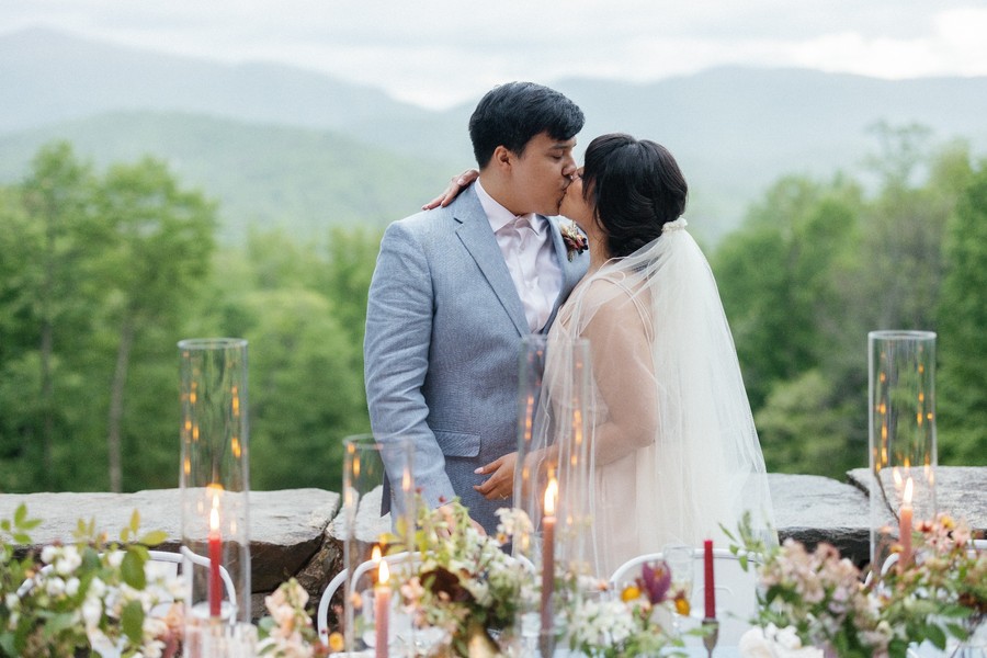 Bride and groom share a kiss on the Lodge Porch at Laurel Falls mountain wedding venue.