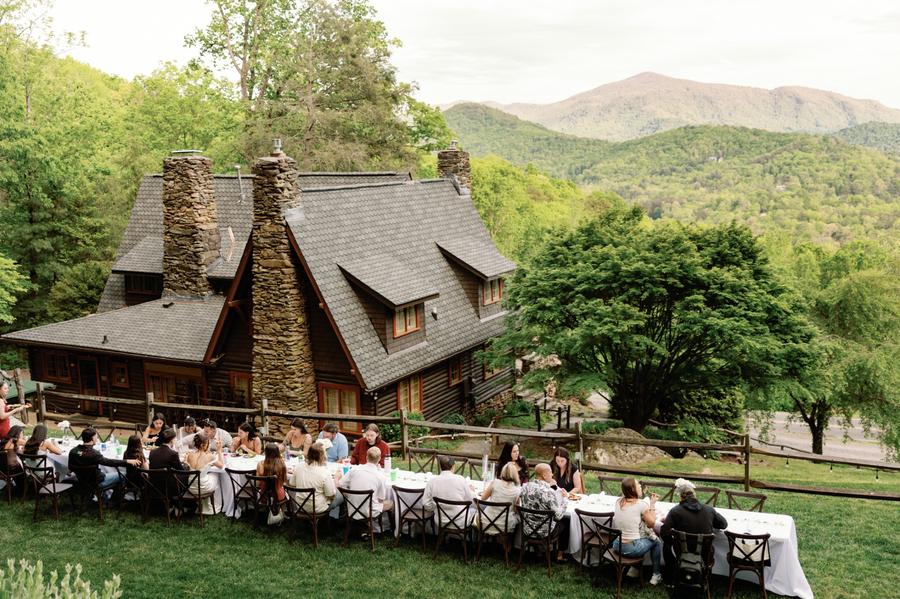 Outdoor wedding reception dinner with mountain views at Laurel Falls. The Lodge which is the largest of the four homes on property is in the background.