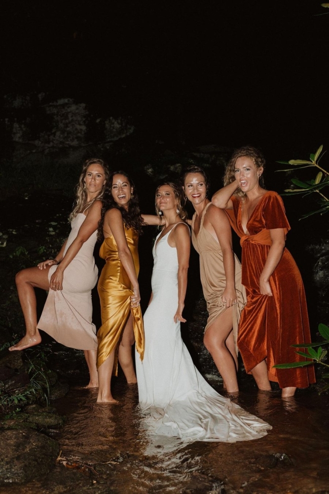 Bride and bridesmaids posing barefoot in waterfall at Laurel Falls at night