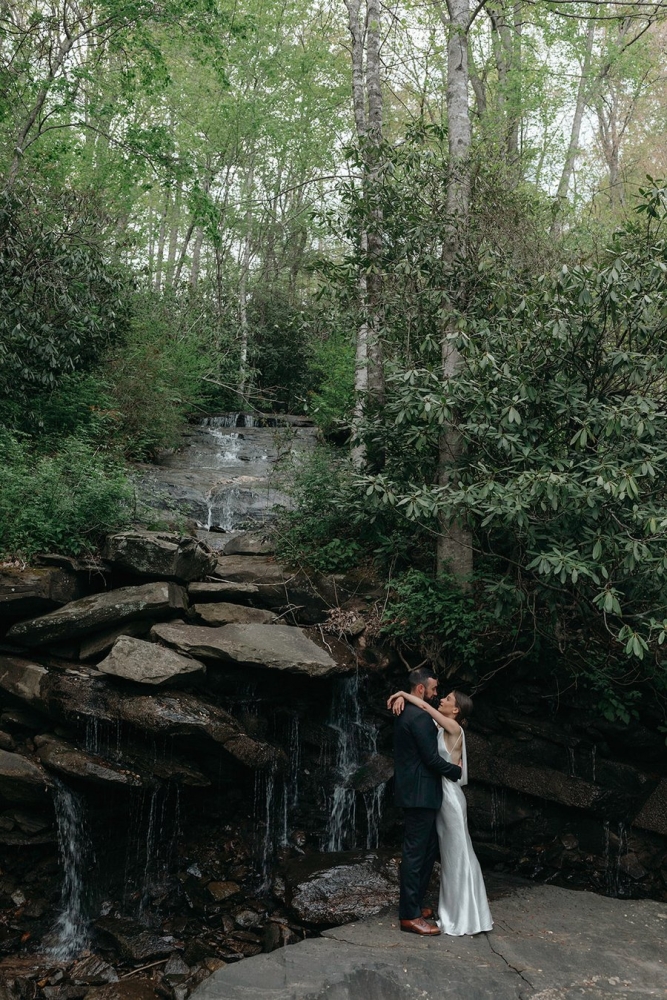 Couple standing beneath forest waterfall at Laurel Falls wedding venue