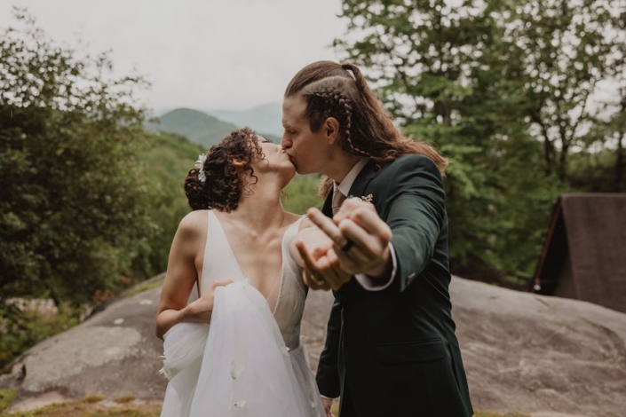 Couple kissing on a rock overlook with Blue Ridge Mountains in the background at Laurel Falls.