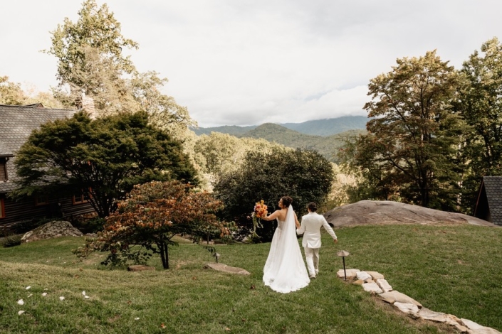 Newlyweds walking together on the lawn at Laurel Falls with mountain views