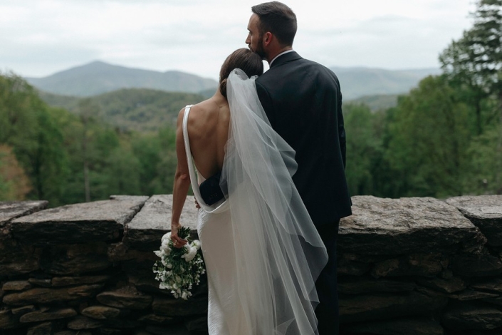 Bride and groom look out over the Blue Ridge Mountains from Laurel Falls in Asheville North Carolina.