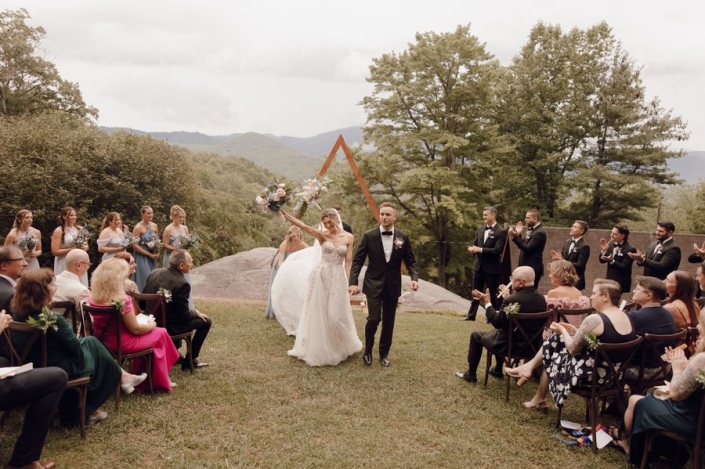 Newly married co.uple walking down the aisle at a mountain wedding ceremony.