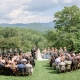 Outdoor mountain wedding ceremony at scenic wedding venue with lawn seating, bride and groom exchanging vows overlooking Blue Ridge Mountain views.